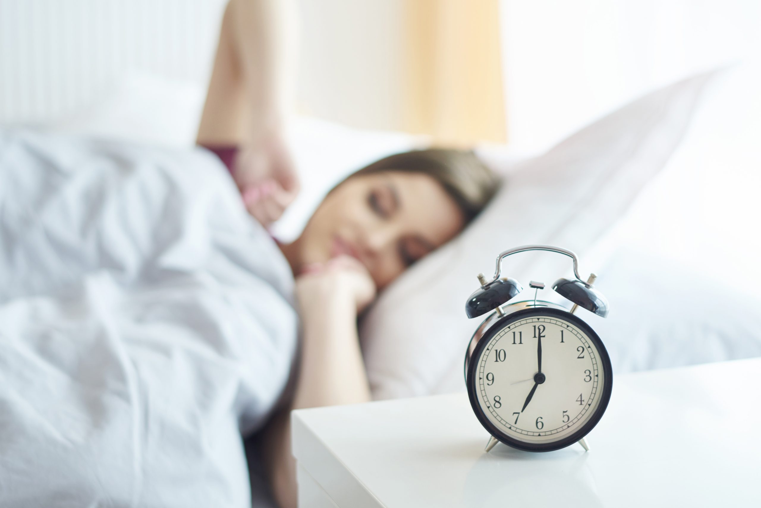 woman lying on bed with a clock
