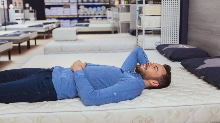 Caucasian man testing mattress in a store