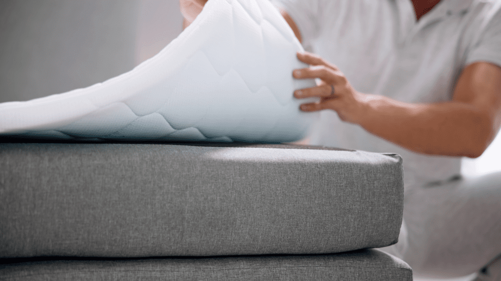 A female hand lifting the foam layer of a mattress.