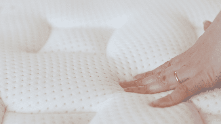 A hand pressing into a plush mattress.